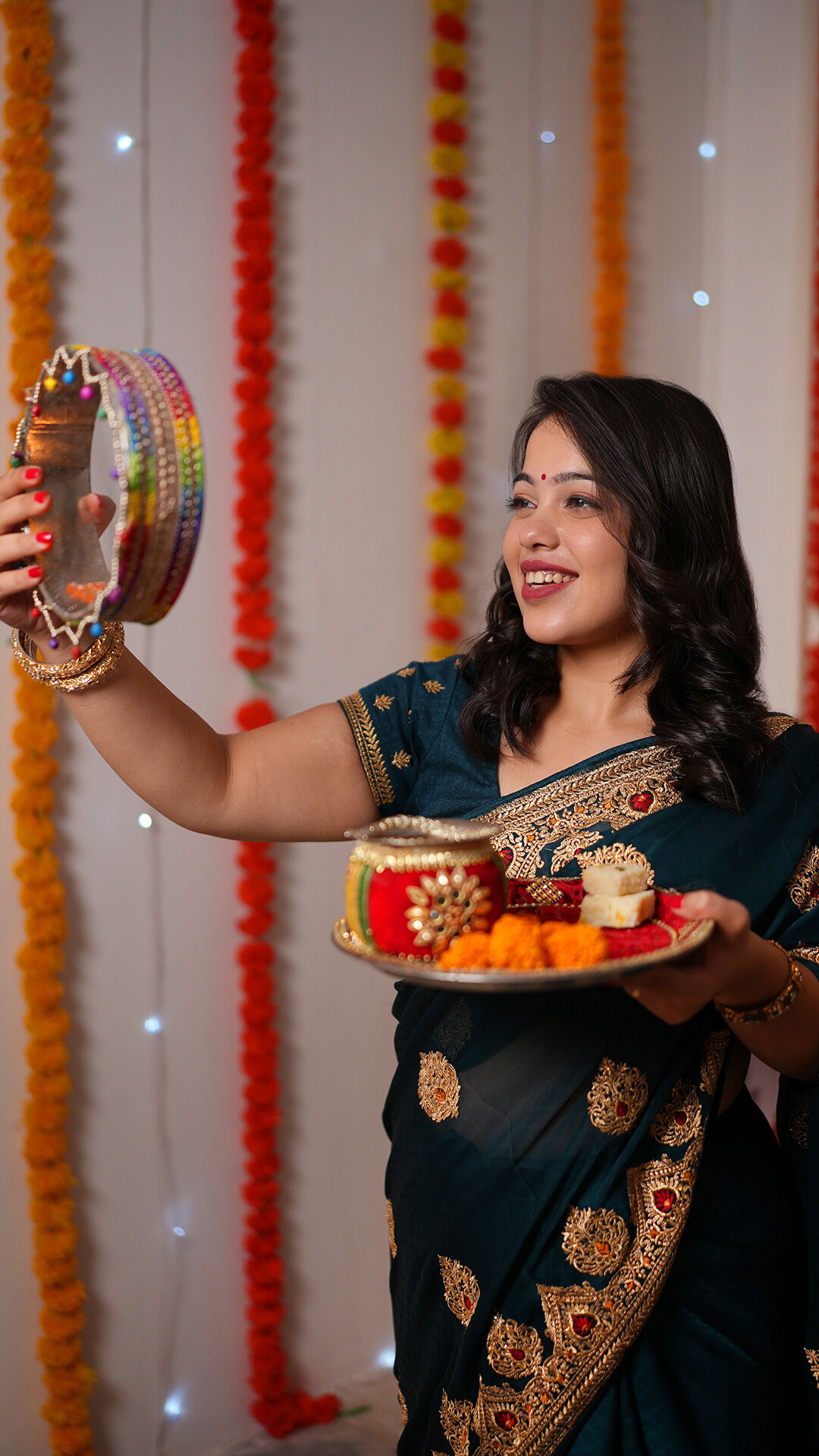 Woman in traditional saree performing Karwa Chauth puja with decorated thali and sieve